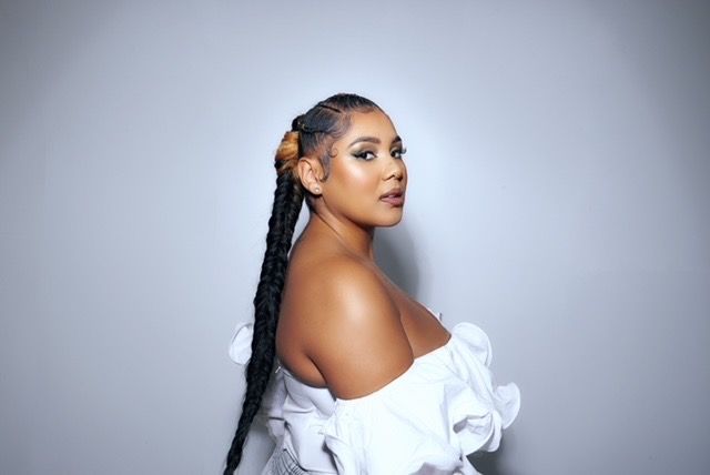 Artiest Cheyenne Toney poseert voor de camera vanaf zijaanzicht en kijkt over rechterschouder de camera in. Haar Haar zit in een lange vlecht.