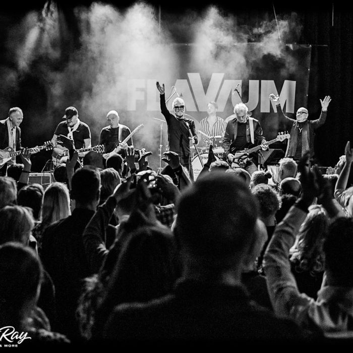 Flavium on stage met publiek op de voorgrond, foto zwart wit