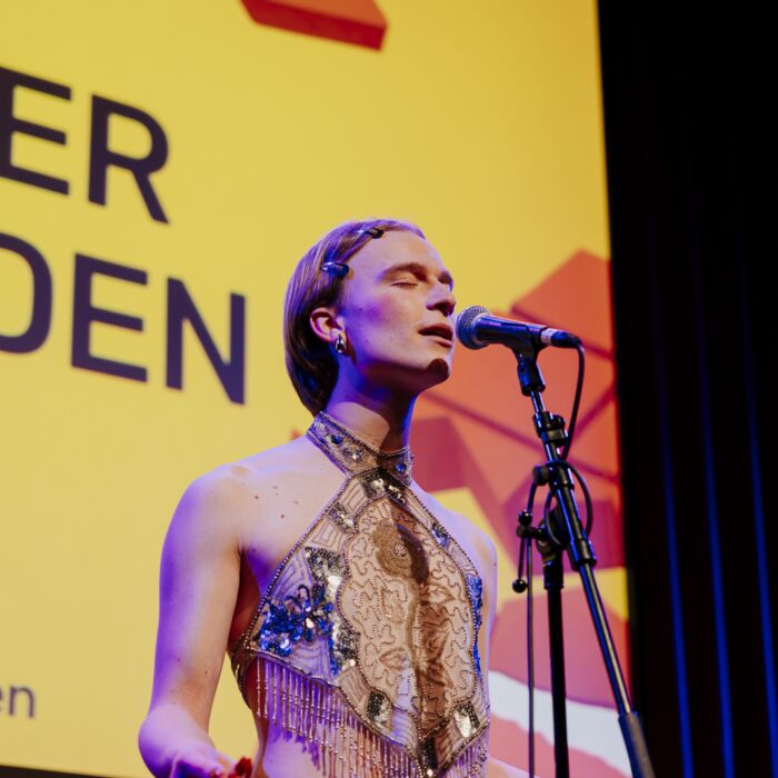 Woordkunstenaar Vlinder Verouden performt geconcentreerd met ogen dicht en handen achter diens rug.