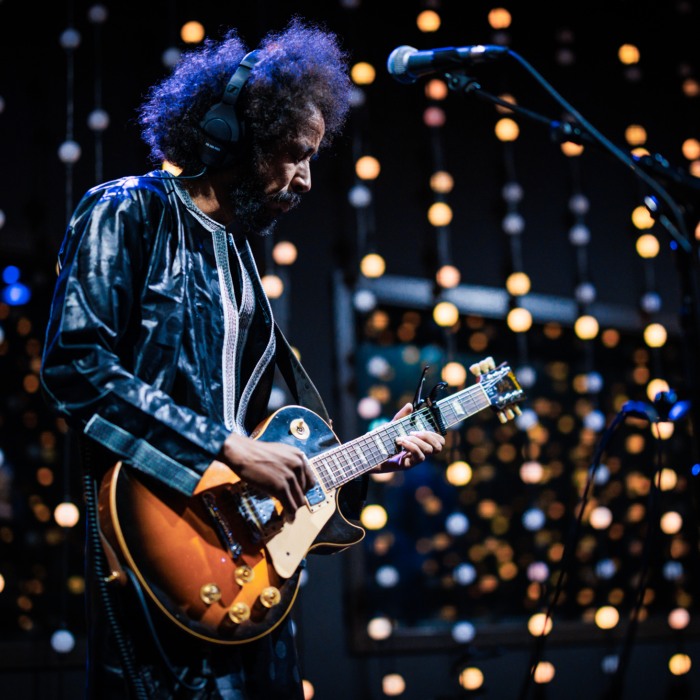 Frontman van rockband Tamikrest speelt gitaar met glinsterende achtergrond