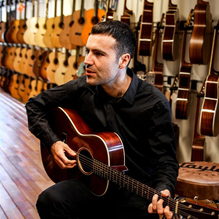 Ground Up artiest Oscar Peris speelt gitaar in een gitaarwinkel