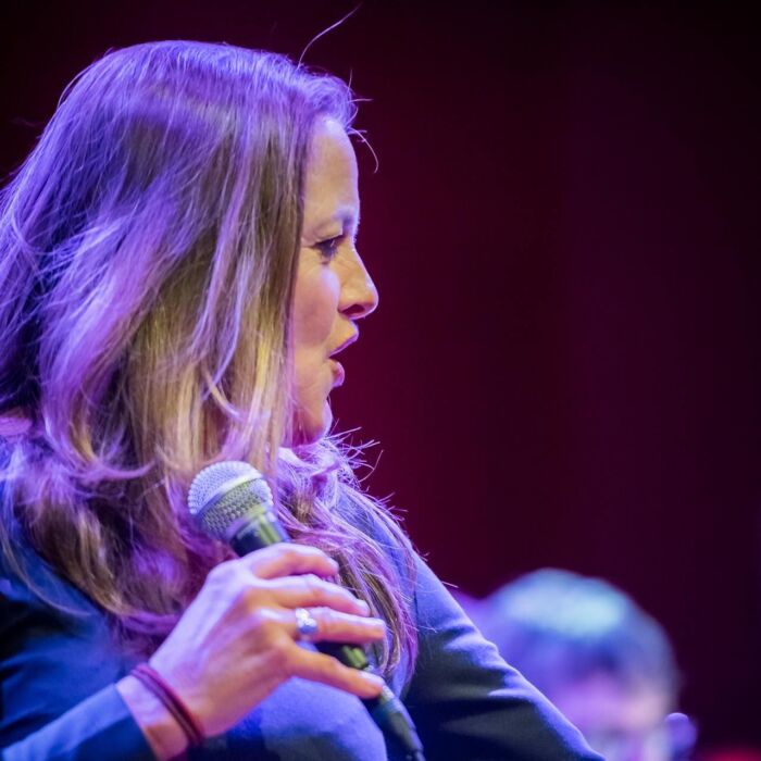 Zangeres Marie José Tiemstra staat op het podium met een microfoon in de hand