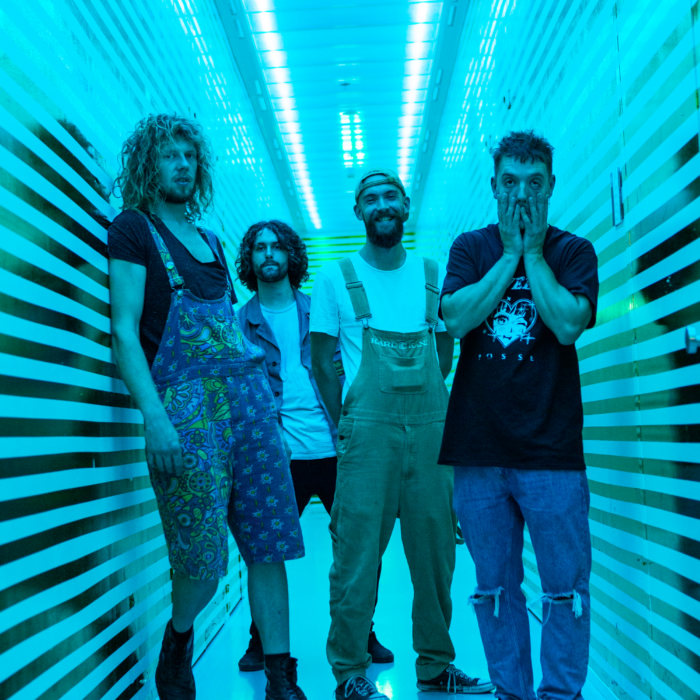 Bandleden Wasted Youth Club staan in blauw belichte gang