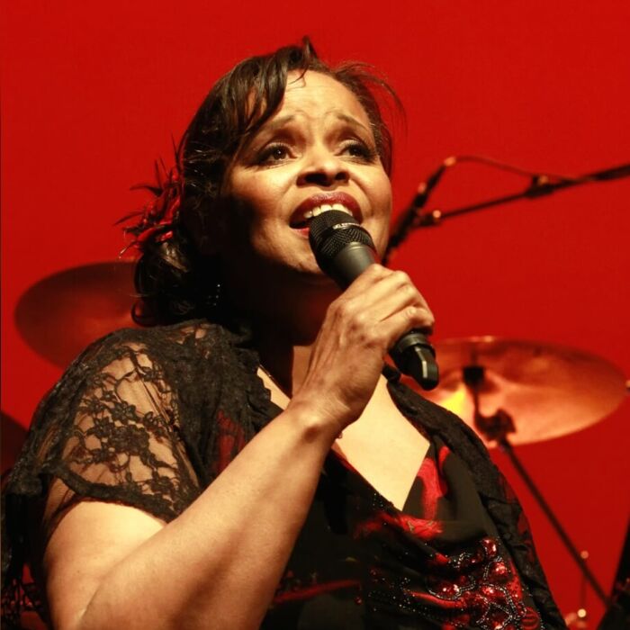 Jazzangeres Deborah Carter zingt in de microfoon met rode achtegrond