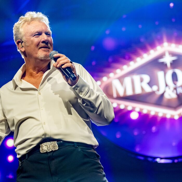 Tom Jones tribute-zanger Robby Griekspoor performt op het podium met microfoon in de hand.