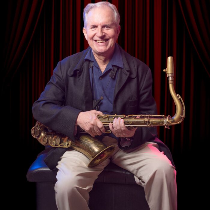 Tenorsaxofonist Scott Hamilton poseert zittend en lachend met saxofoon in de hand