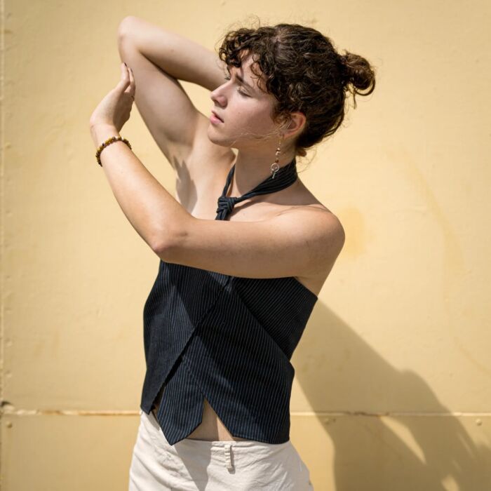 Coos staat in de zon in een kunstzinnige semi-reclame-achtige pose met als achtergrond een gele muur.