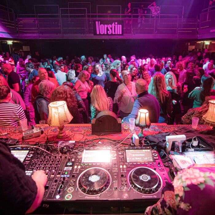 Sfeerbeeld dansfeest VroegZat, dj draait achter de booth en kijkt uit naar een zee dansende mensen