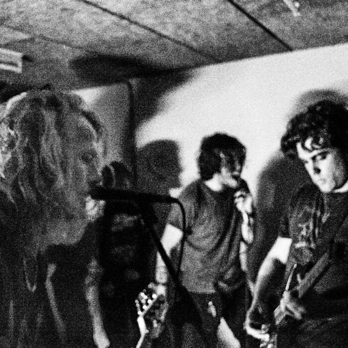 Zwartwit-foto van bandleden aquelarre* muziek aan het maken zijn.