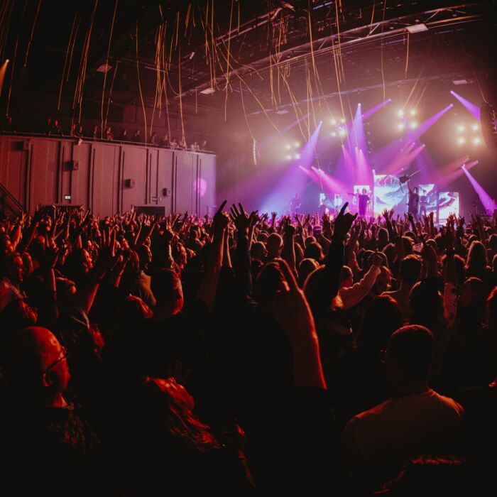 Energieke livefoto van een volle zaal en optredende band op de achtergrond