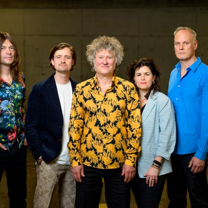 Eric Vloeimand poseert met bandleden voor de camera in vrolijke gele blouse