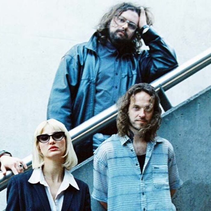 De bandleden van Hiqpy staan op een trap tegen een grijze achtergrond.