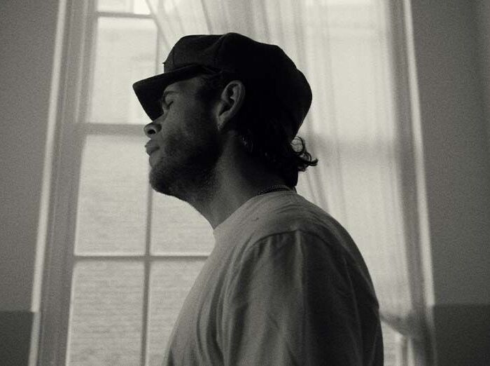 Michael Prins kijkt peinzend het beeld uit en draagt een kek hoedje