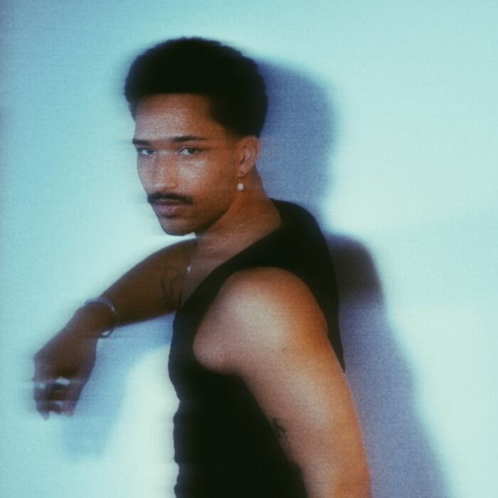 Blurry foto van artiest Tos, die naar links loopt maar in de camera kijkt.