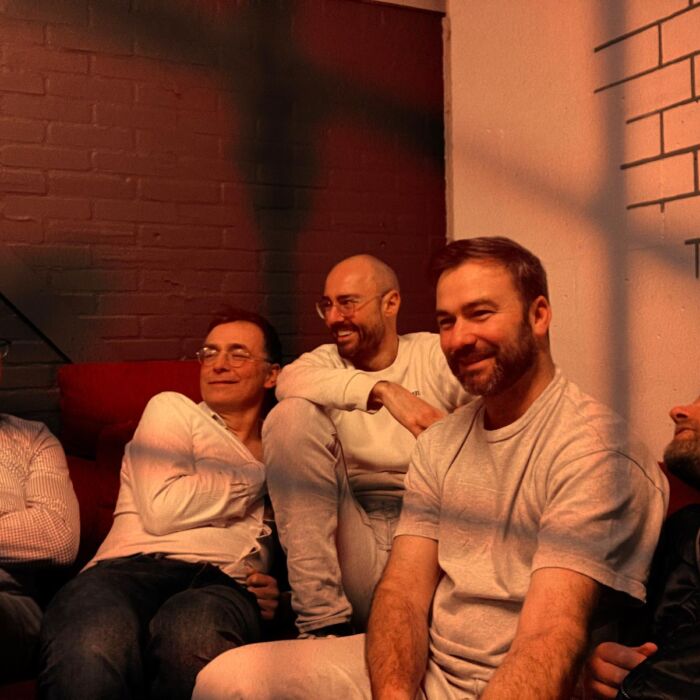 Bandleden van Francis! hangen lachend op een bank.