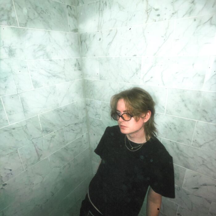 Daniel Brooke in een grijswitte omgeving die lijkt op een goederenlift