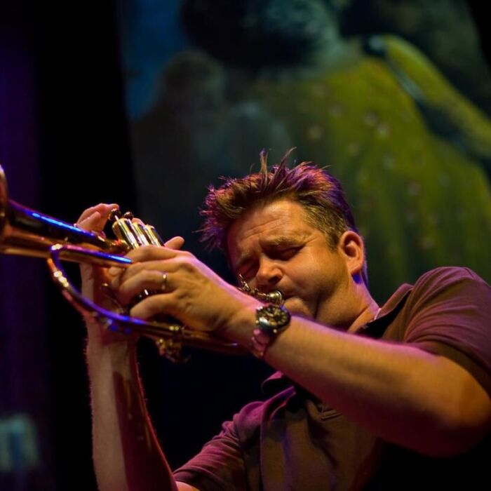Jan Wessels speelt trompet op podium, met ogen dicht.