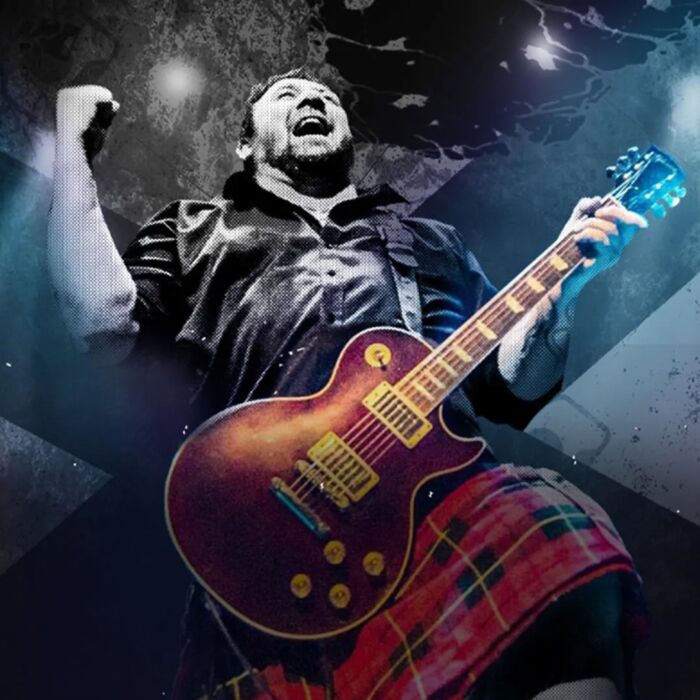 Half zwart-wit half kleurenfoto van frontman van King King, hij heeft een electrische gitaar in de hand en een rood geruite kilt aan.