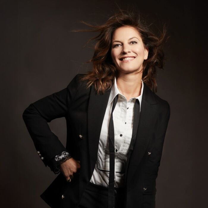 fay lacht naar de camera met één hand op haar heup.