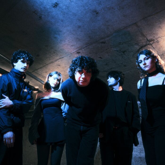 Band Crashing kijkt in camera voorover gebogen. Bandlewden hebben donkere kleding aan.