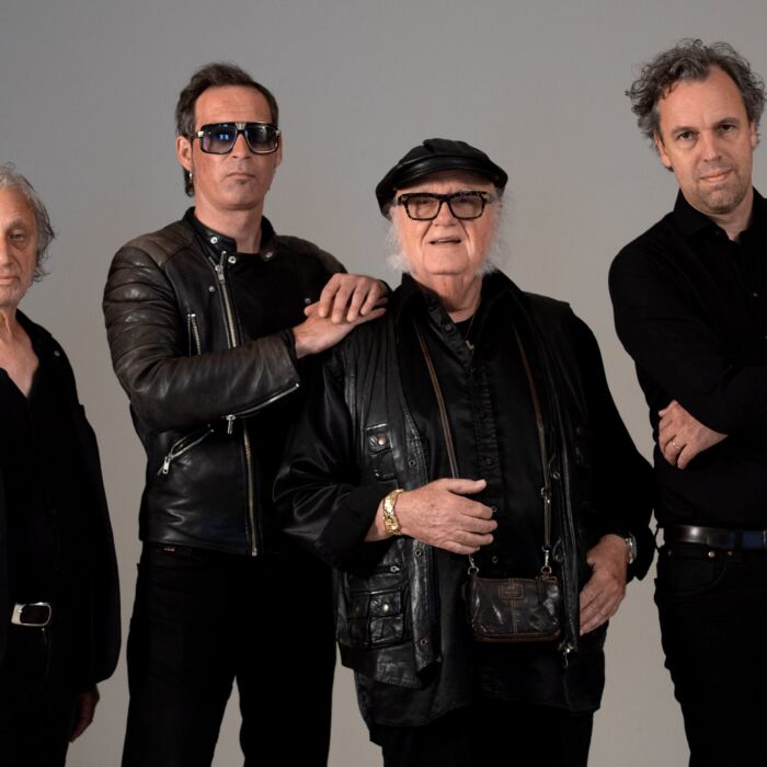 Bandleden Focus poseren voor lichtgrijze achtergrond staand voor de camera in stoere zwarte leren kleding,