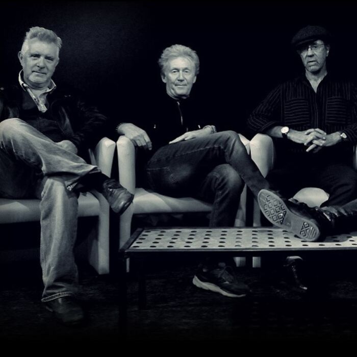 Zwartwit foto van Manfred Mann's Earth Band zittend op een bank