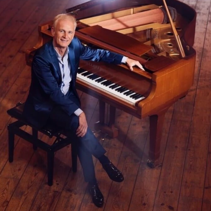 pianist Cor Bakker zit aan een piano